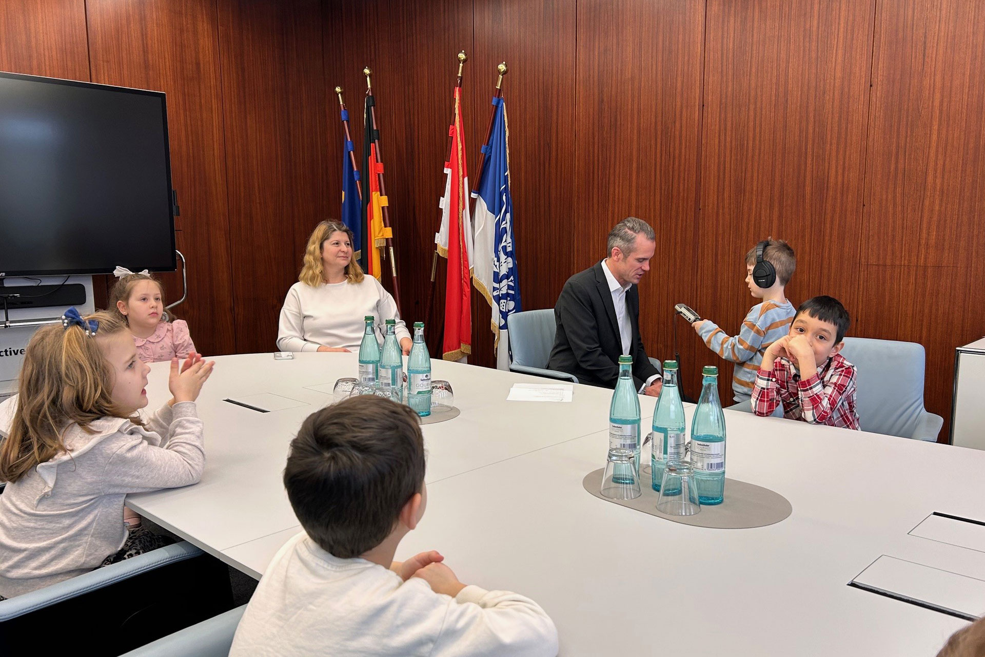 Kinder interviewen Oberbürgermeister Dr. Felix Schwenke mit Aufnahmegerät an einem Konferenztisch im Rathaus.
