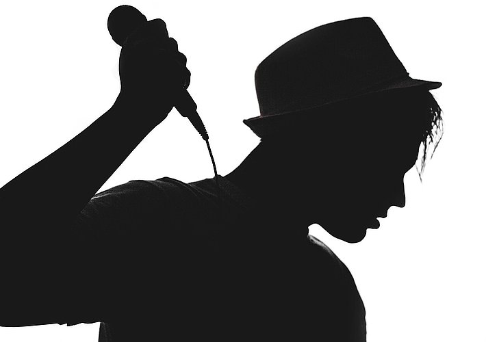 Musiker hält Mikrofon. Bild in schwarz-weiß.
