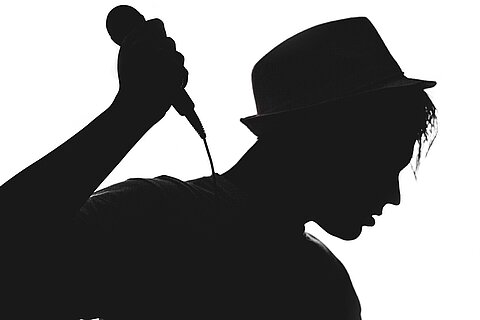 Musiker hält Mikrofon. Bild in schwarz-weiß.