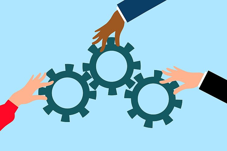 Drei Hände mit unterschiedlichen Hauttönen arbeiten zusammen, um drei Zahnräder zu verbinden, und symbolisieren Teamwork und Zusammenarbeit vor einem hellblauen Hintergrund.