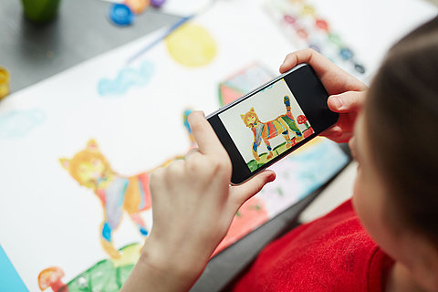 Schoolgirl photographing her painted picture for blog