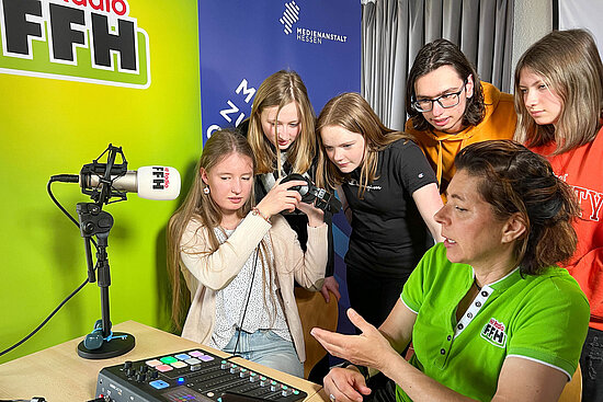 Radiomoderatorin erklärt Gruppe Jugendlicher die Arbeit im Studio
