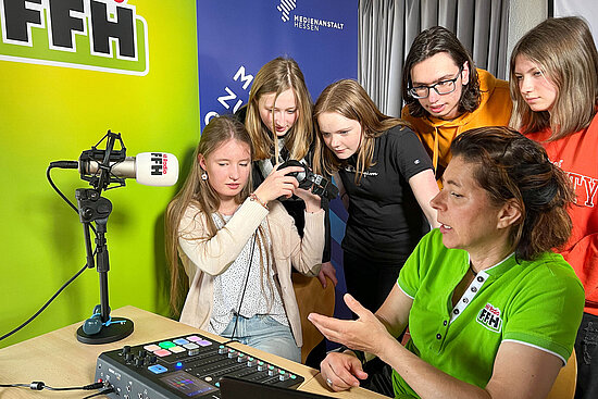 Radiomoderatorin erklärt Gruppe Jugendlicher die Arbeit im Studio