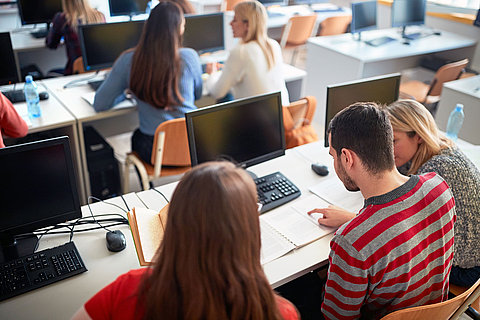 students studying on university campus using computer in class
