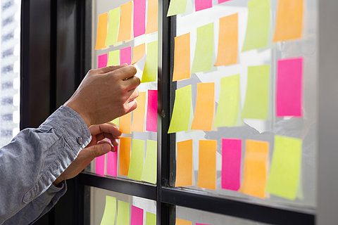 Man attaching sticky note to scrum task board in the office