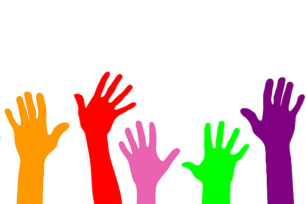 erhobene Hände in verschiedenen Farben (orange, rot, rosa, grün, lila), die sich vor einem weißen Hintergrund nach oben strecken und Vielfalt, Teilhabe oder ehrenamtliches Engagement symbolisieren